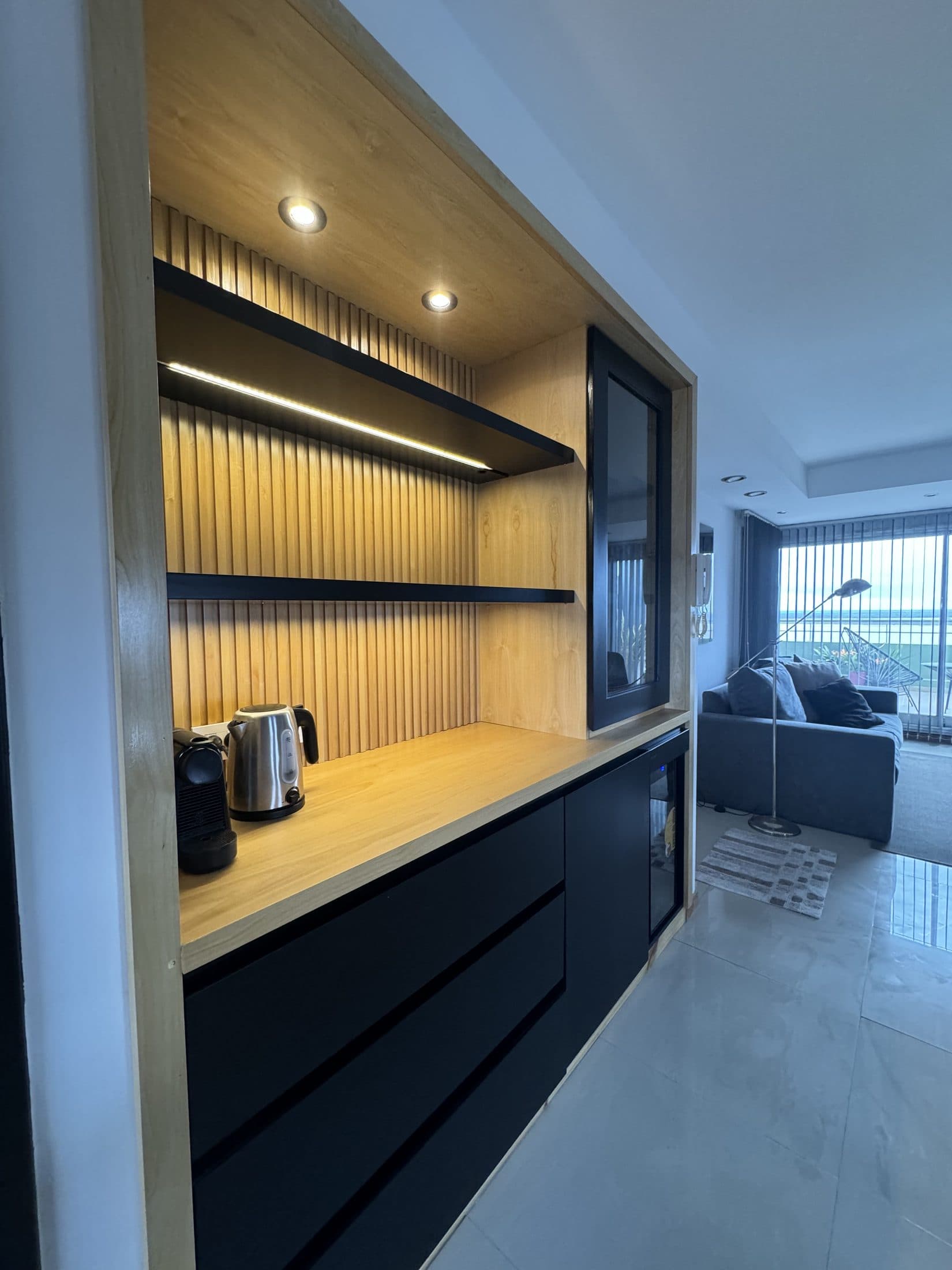 Mueble multifunción de madera que articula cocina y dormitorio en el loft de Colón