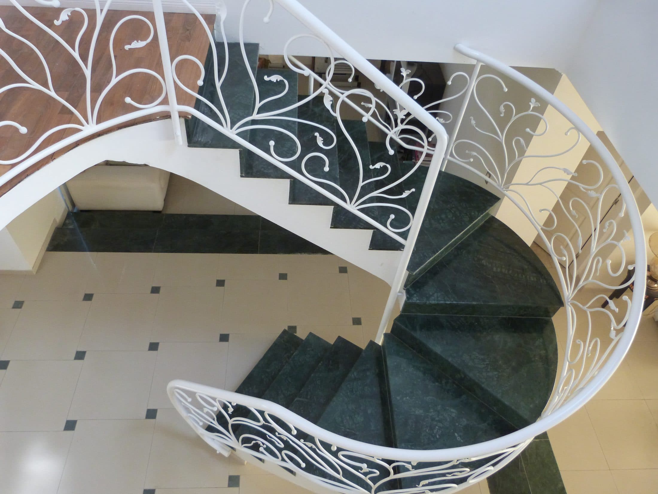 Escalera caracol con baranda de herrería a medida bajo un lucernario circular